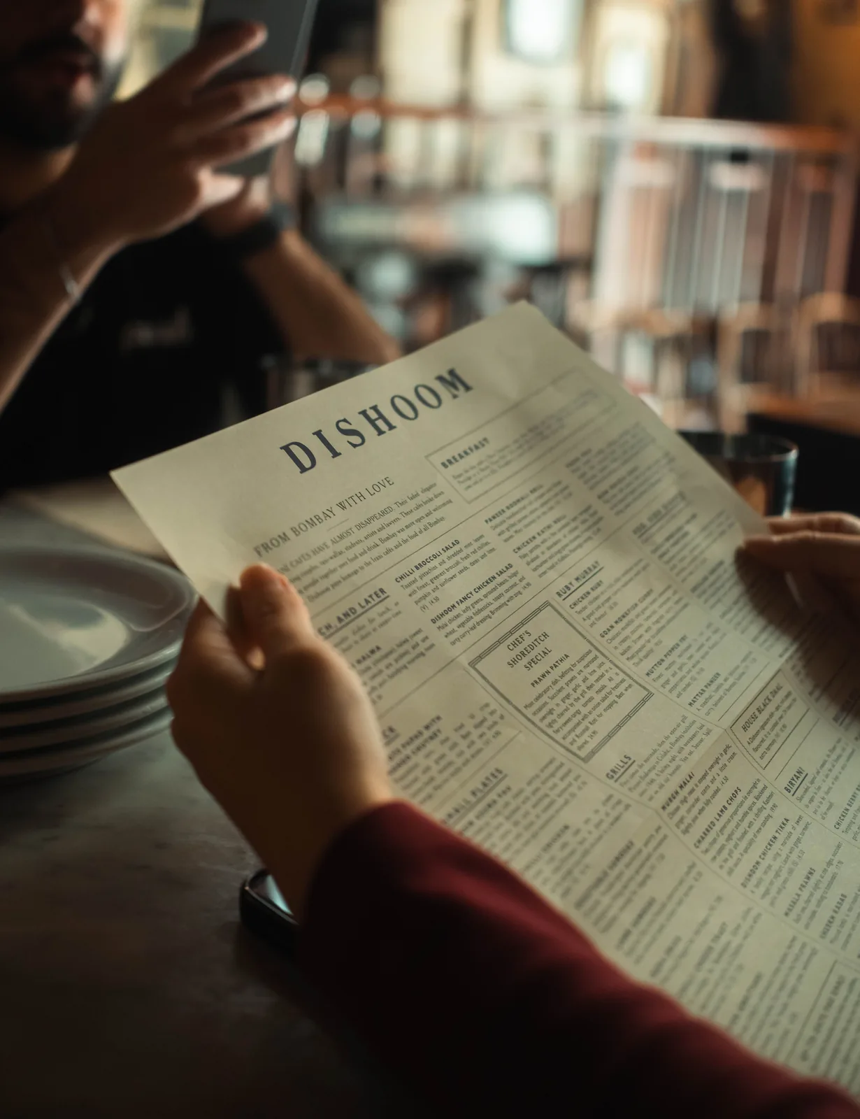 Hand holding an open restaurant menu at a table