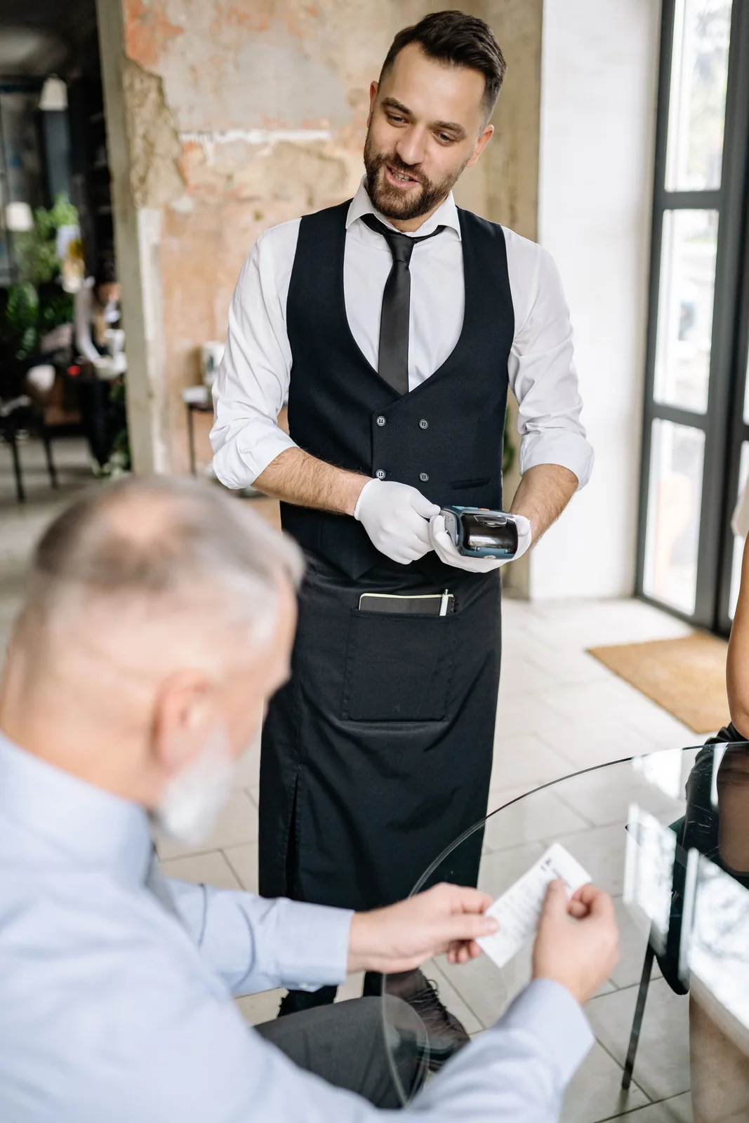 Waiter serving food with a gloved hand at a fine dining restaurant