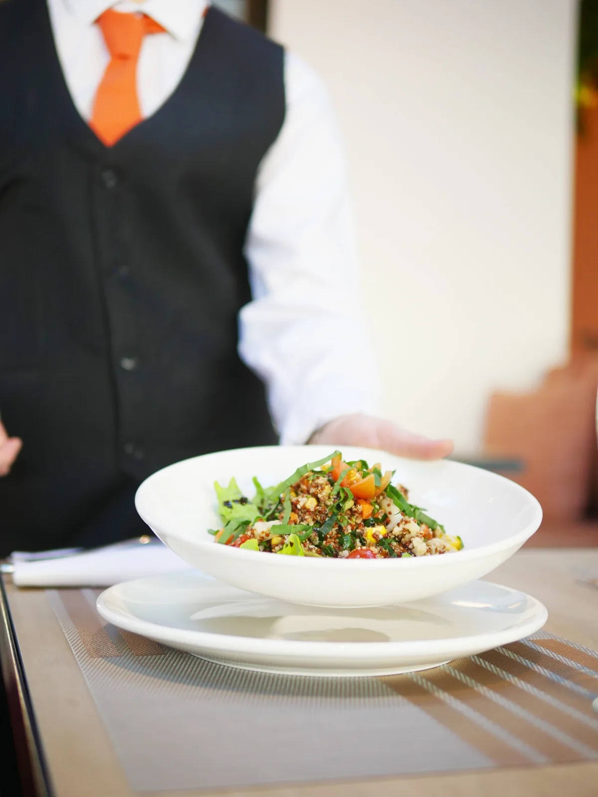 Waiter serving a plate at a restaurant table