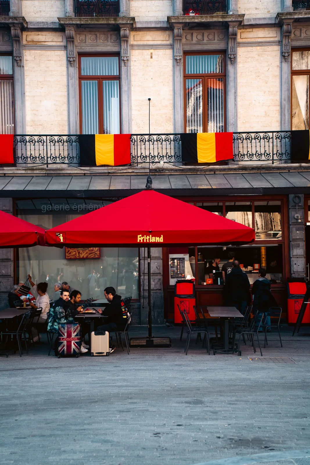 Outdoor cafe with red umbrellas in a European plaza, Belgium