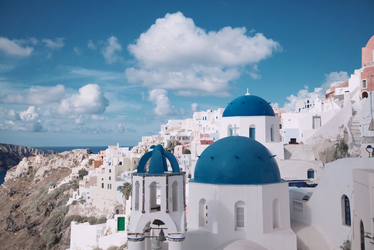 Santorini white-washed buildings with a blue dome overlooking the Aegean Sea: Greece food allergy travel guide