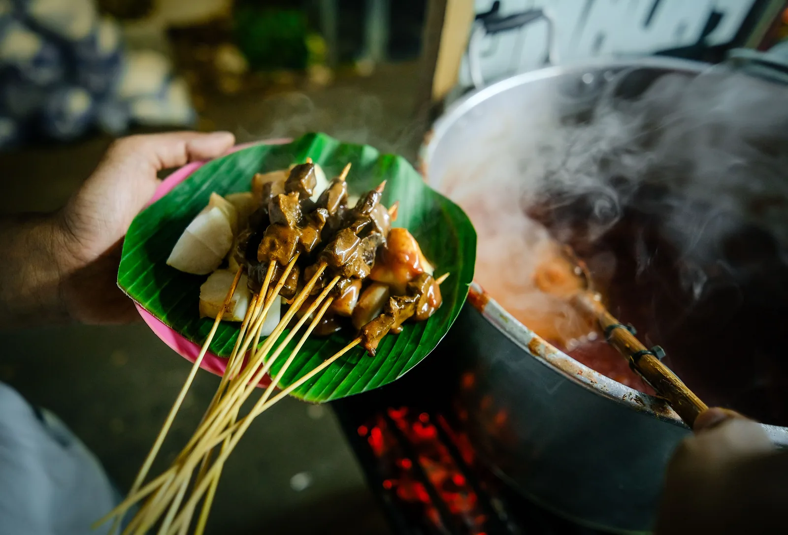 Hand holding grilled satay skewers
