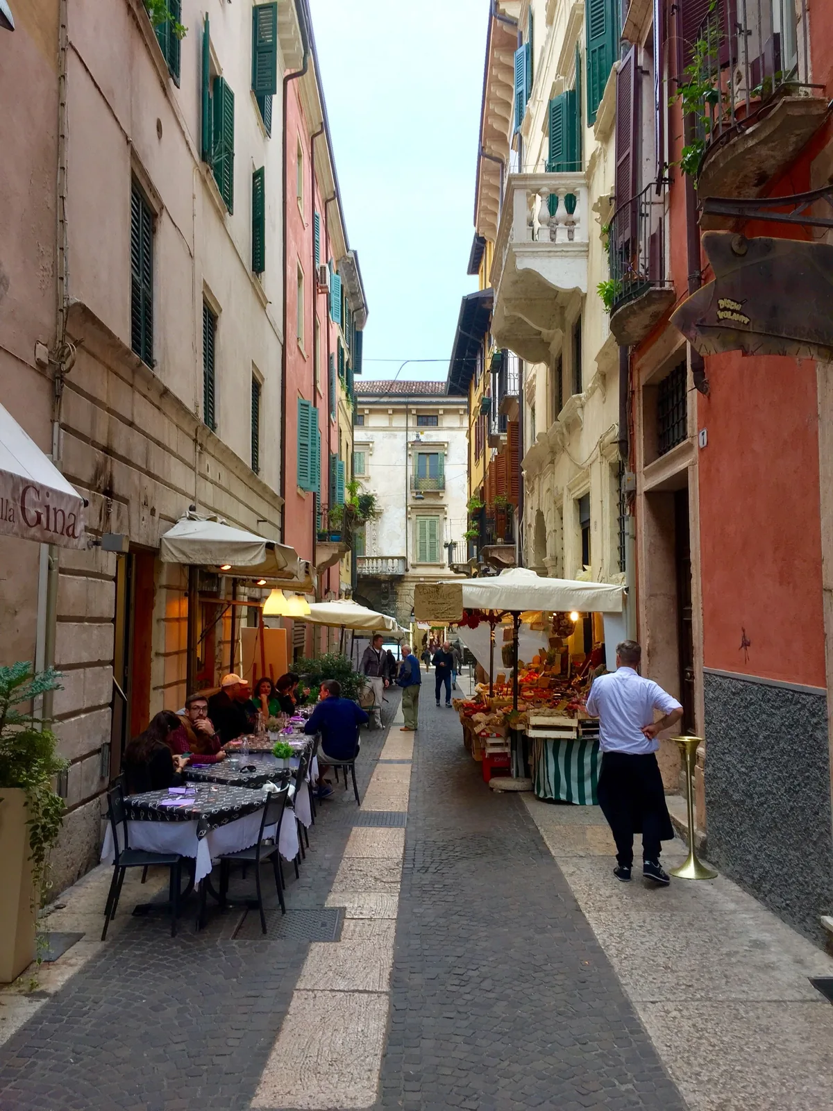 Outdoor restaurant seating on a narrow street in Italy, the kind of table where a written allergy card gets handed to the kitchen