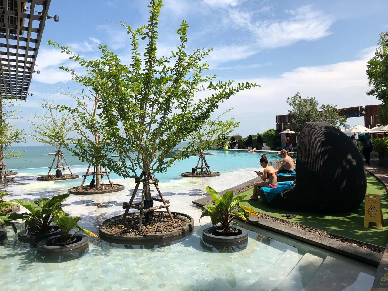 Outdoor infinity pool at a Thai wellness resort surrounded by tropical vegetation