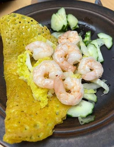 Banh xeo sizzling pancake with visible shrimp, a common shellfish allergen source in Vietnam
