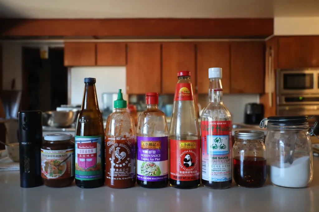 Vietnamese pho condiment table with hoisin, fish sauce, and chili, hidden allergen sources