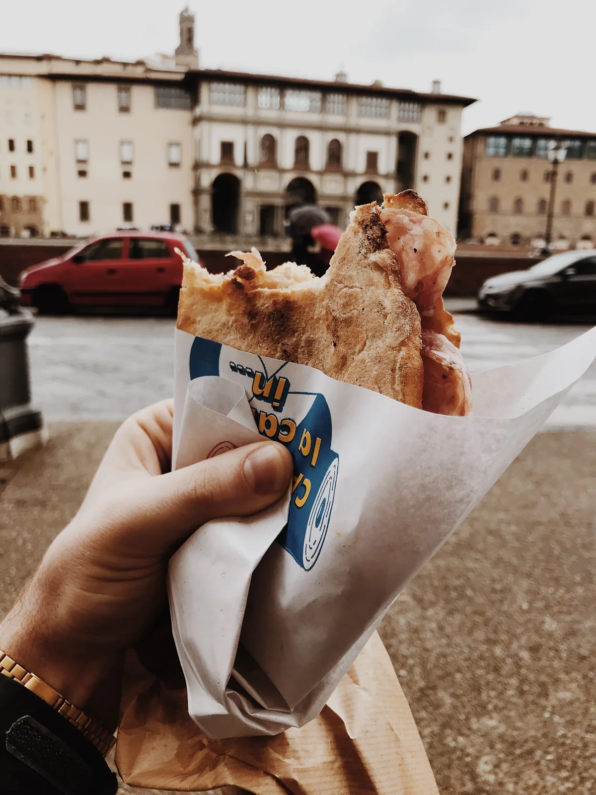 Hand holding a pastry in a European town square