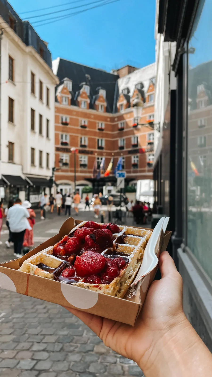 Hand holding a takeaway food box on a European street