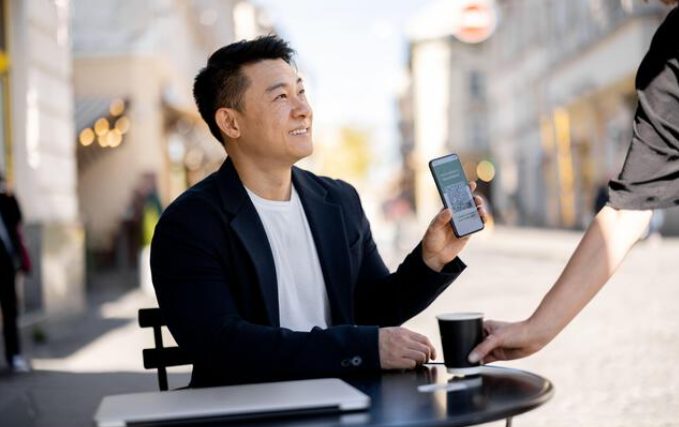 Traveler showing digital allergy card to restaurant server abroad