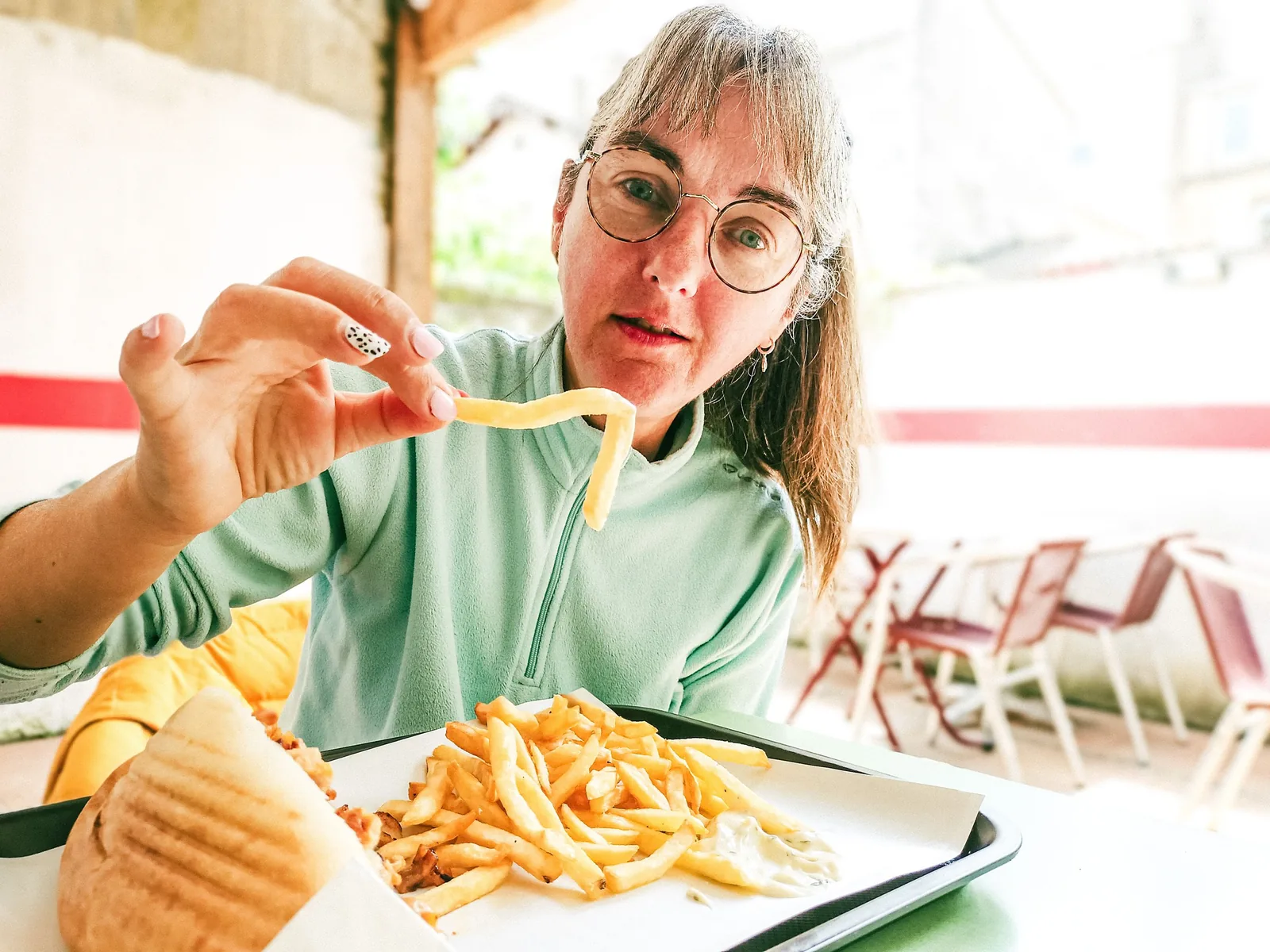 Woman eating fries and a sandwich in a restaurant